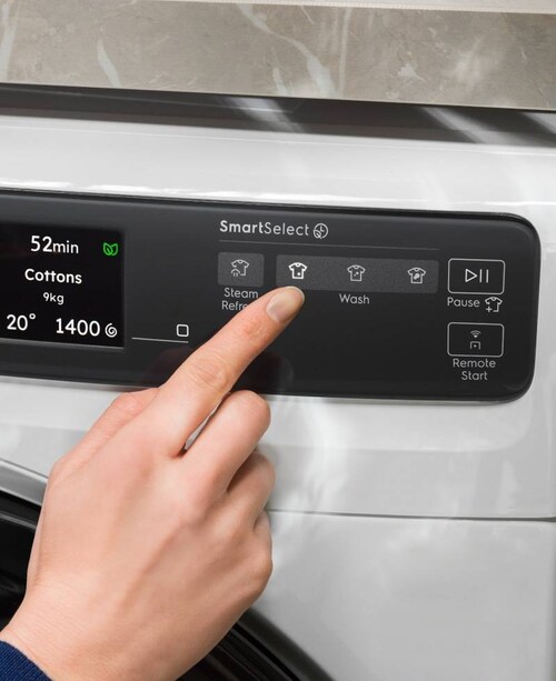 Person adjusting control panel on an Electrolux washing machine.
